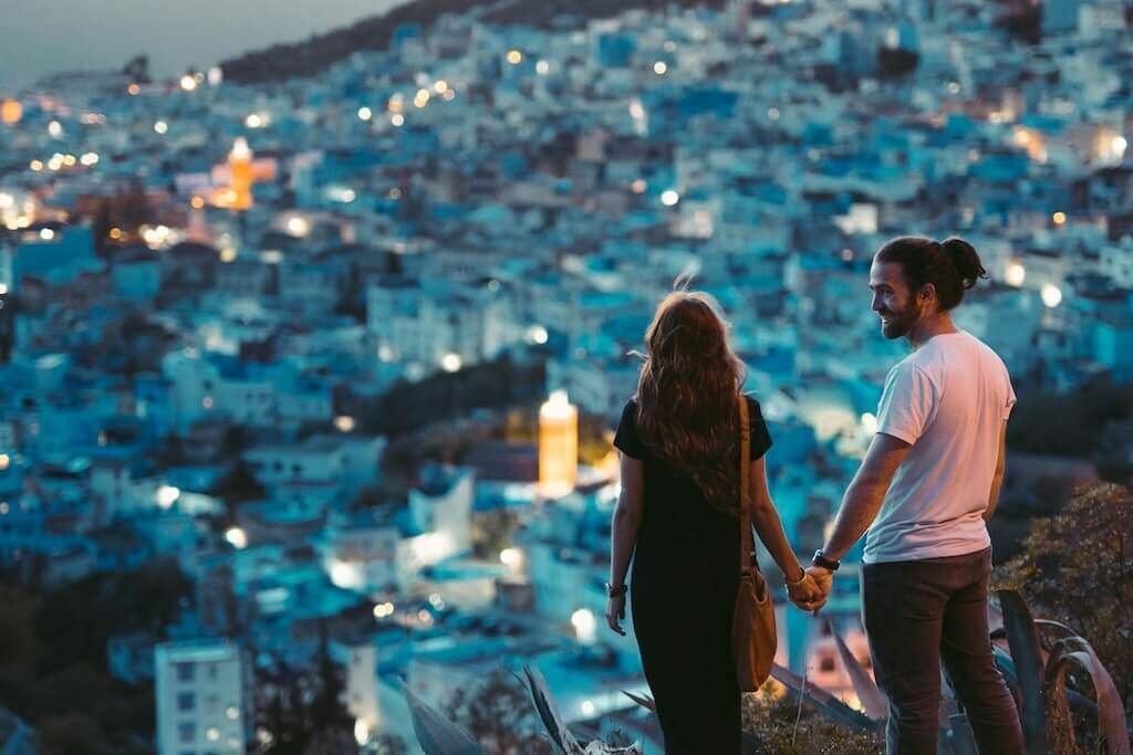 Pareja contemplando una ciudad marroquí al atardecer