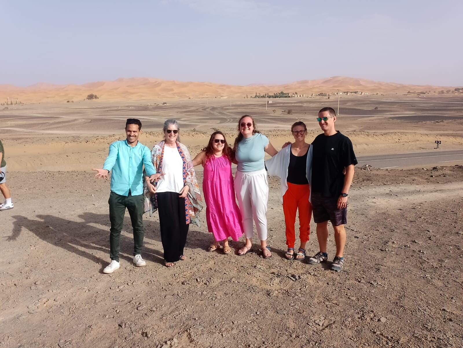 Grupo de viajeros posando juntos en el desierto de Marruecos